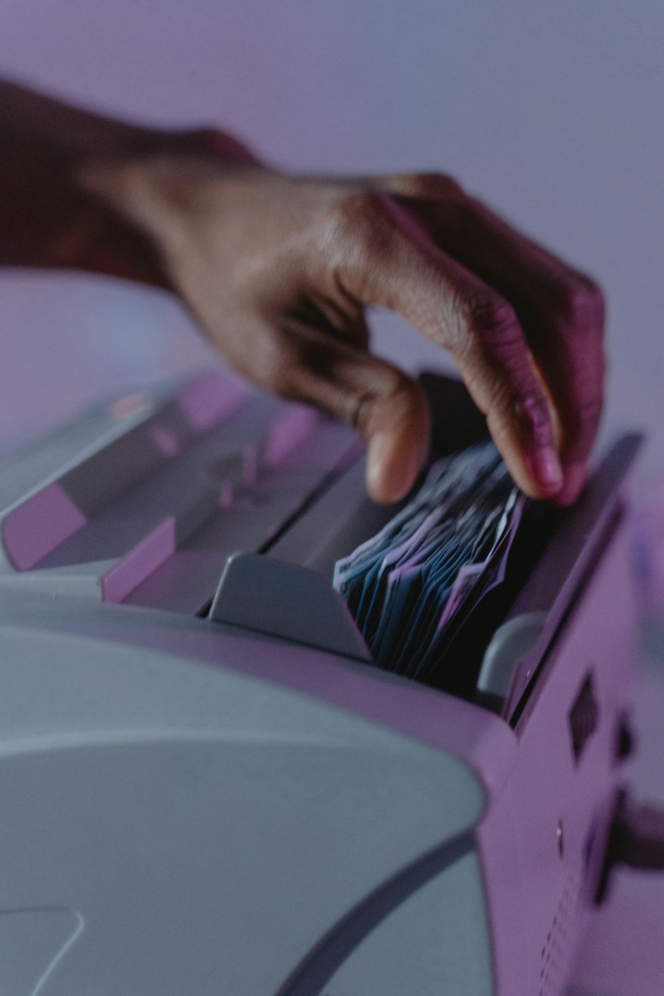 A hand operates a money counter, sorting banknotes efficiently.